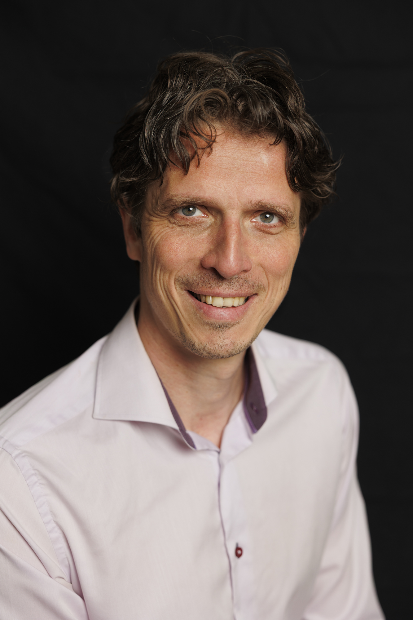 Laurens de Groot in grijs pak, lachend, tijdens een training