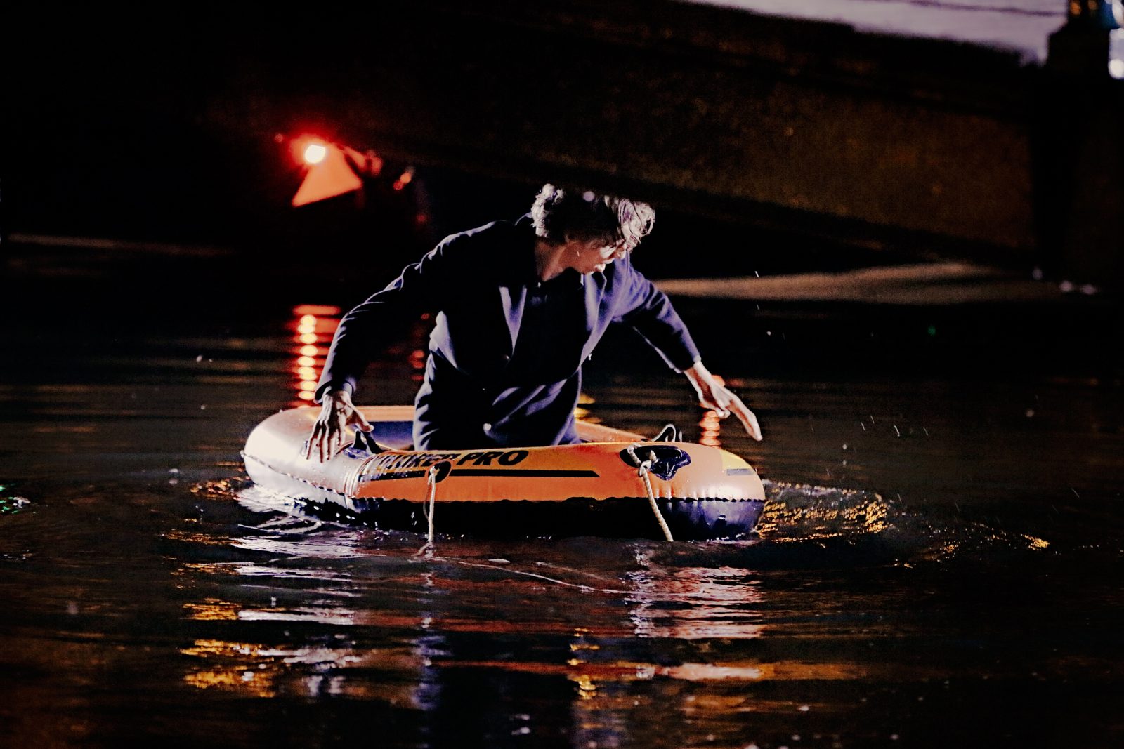 Laurens de Groot in een rubberboot met lamp op een gracht bij nacht